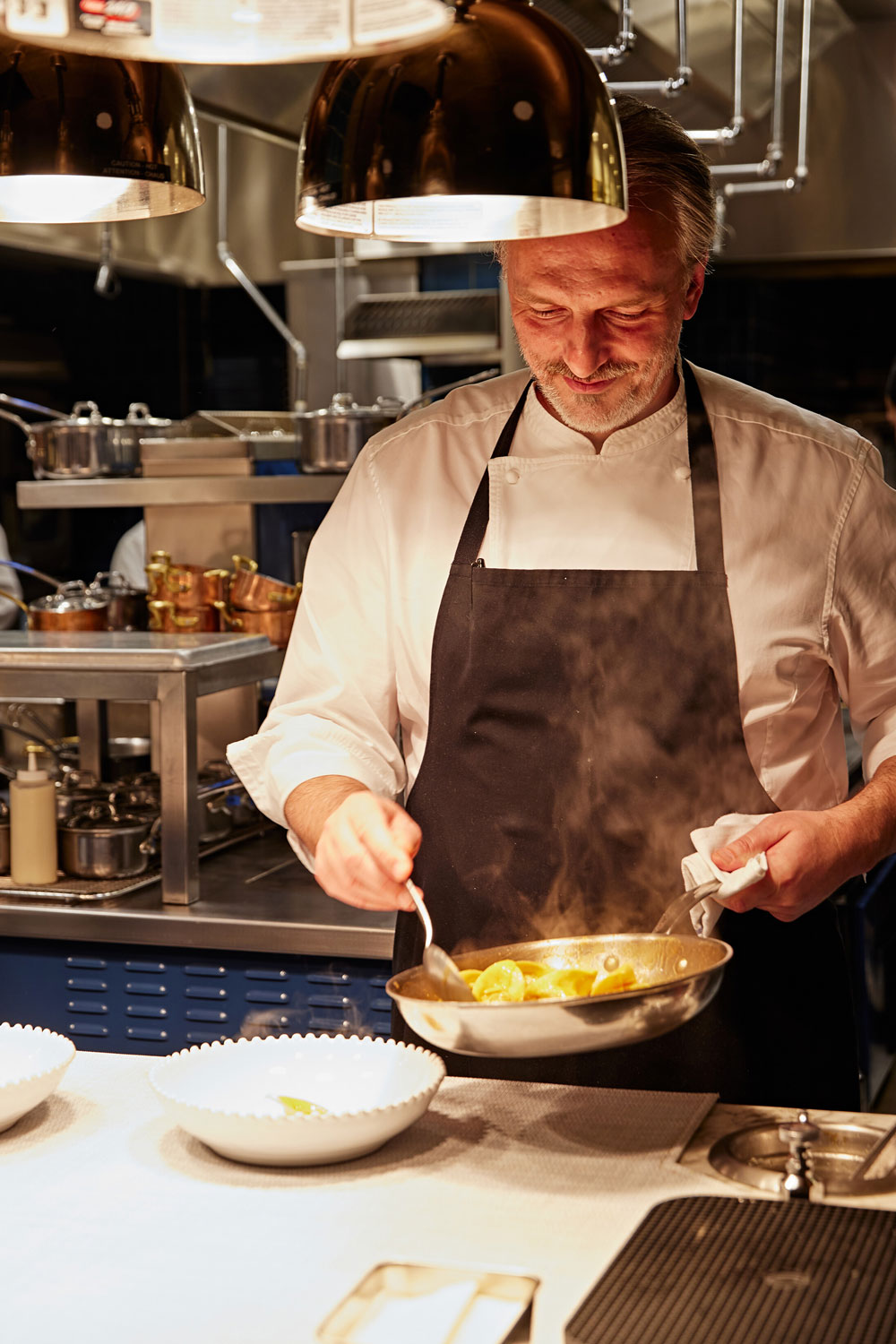 Chef Carmellini with a pan in hand in the kitchen