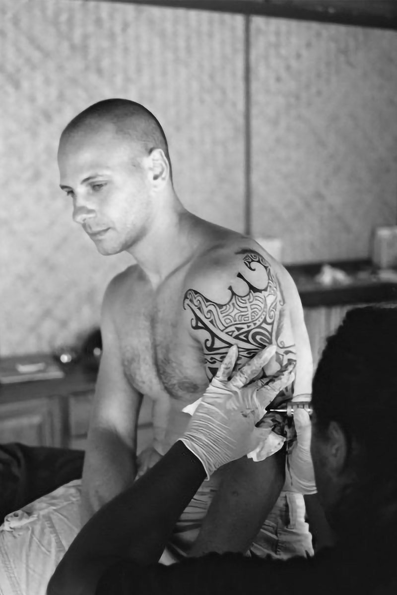 A portrait of David getting a tattoo in Moorea in French Polynesia while on assignment for Budget Travel.