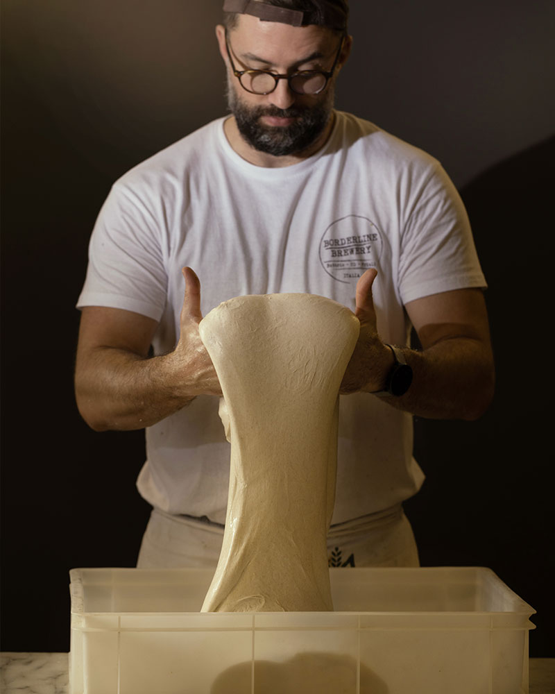 Andrea Chittaro folding bread dough; he is one of the partners at Spaccio Pani, a bakery in Via Lazzaretto Vecchio in Trieste