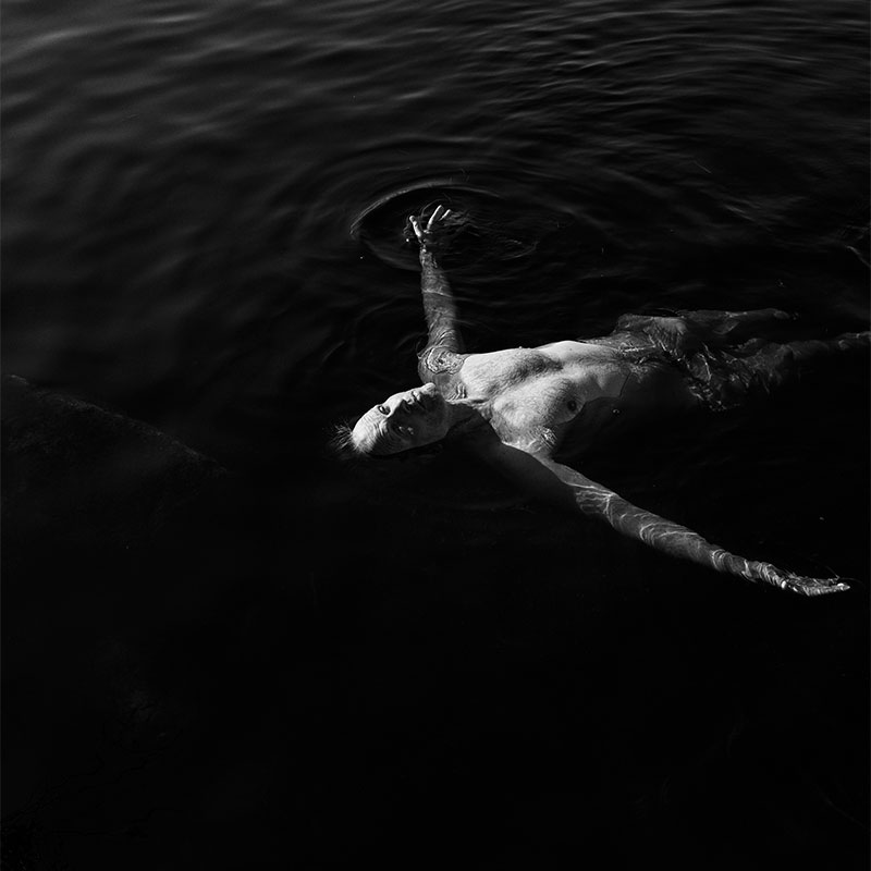 Kagge swimming, floating on his back, in water near his cabin on Blefjell